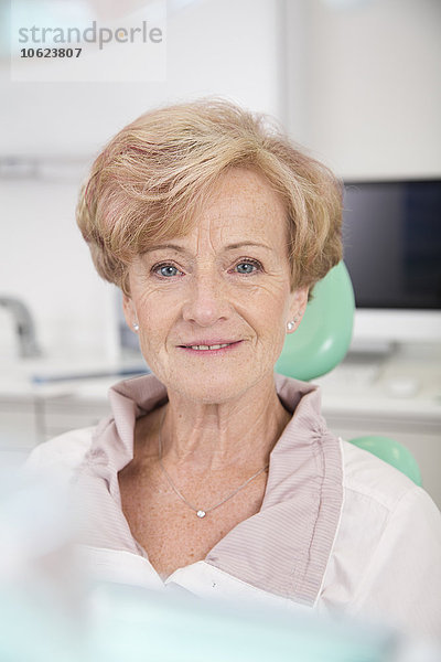 Porträt der lächelnden Seniorin im Zahnarztstuhl