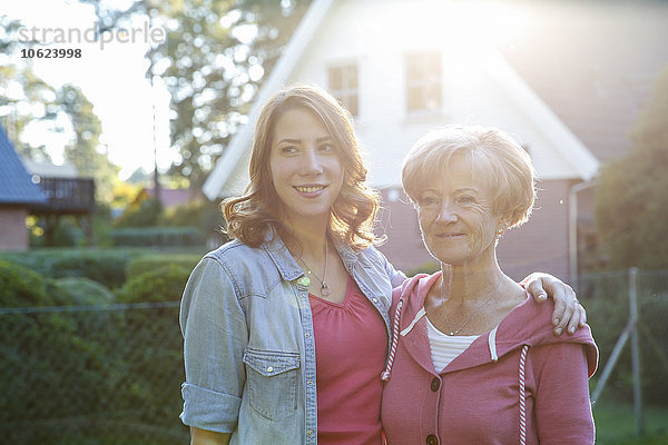 Porträt der lächelnden erwachsenen Tochter mit älterer Mutter im Garten