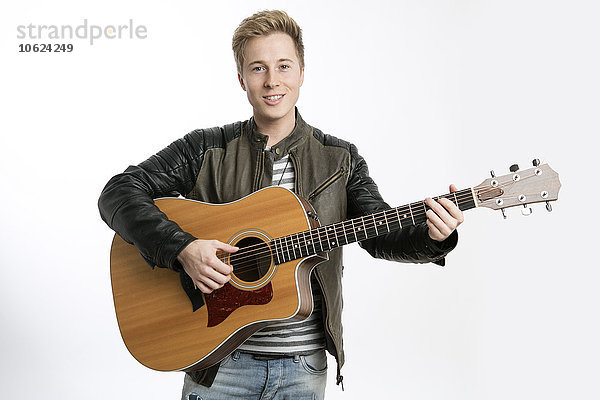 Lächelnder junger Mann beim Gitarrespielen