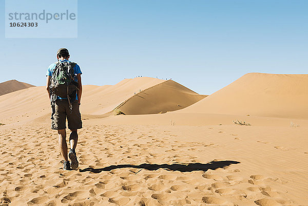 Namibia  Namib Wüste  Mann mit Rucksack wandert durch die Dünen