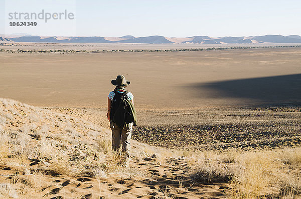 Namibia  Namib Wüste  Sossusvlei  Frau mit Hut und Rucksack mit Blick zum Horizont