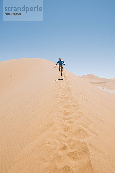 Namibia  Namib Wüste  Sossusvlei  Mann läuft eine Düne hinunter