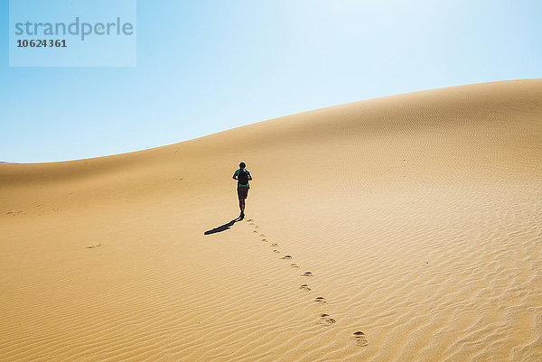 Namibia  Namib Wüste  Sossusvlei  Mann beim Wandern durch die Dünen