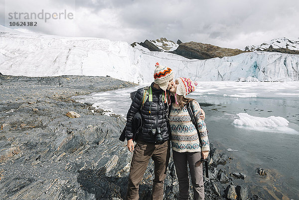 Peru  Paar mit Wollchullos und Küssen vor dem Pastoruri-Gletscher