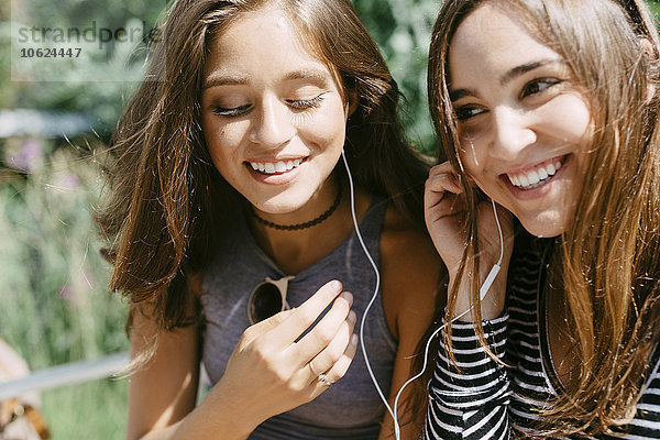 Zwei glückliche Freunde teilen sich Kopfhörer