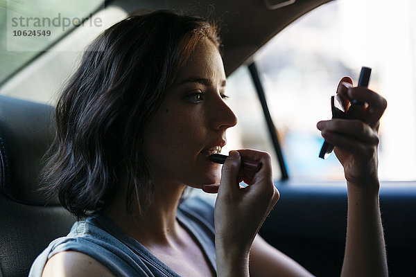 Porträt einer jungen Frau  die sich in einem Taxi schminkt.