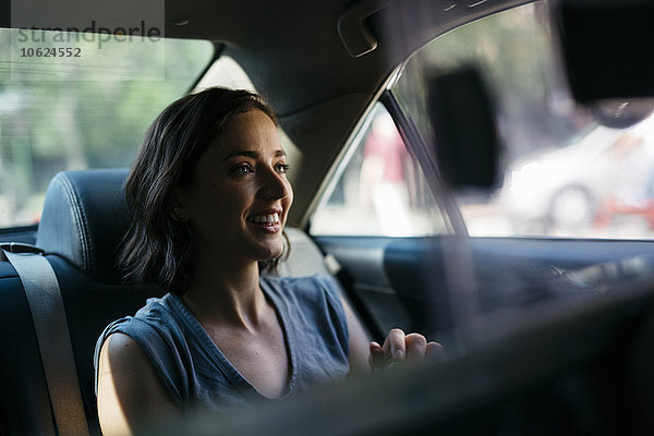 Porträt einer glücklichen jungen Frau  die in einem Taxi sitzt.