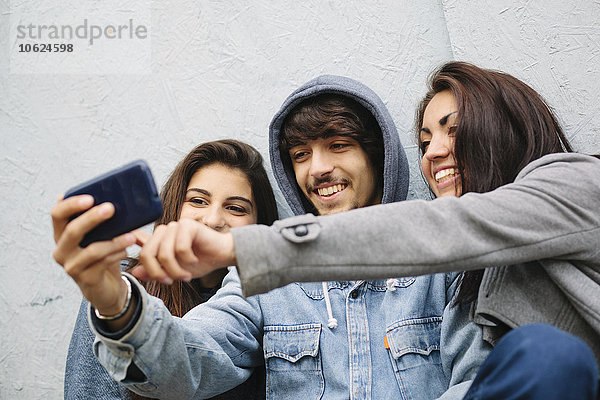 Drei Freunde  die einen Selfie mit dem Handy nehmen.