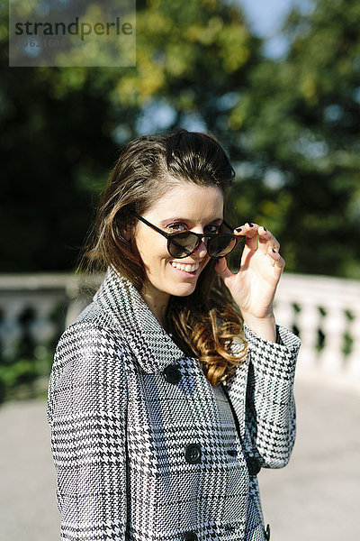 Italien  Vicenza  lächelnde brünette Frau mit kariertem Mantel und Sonnenbrille