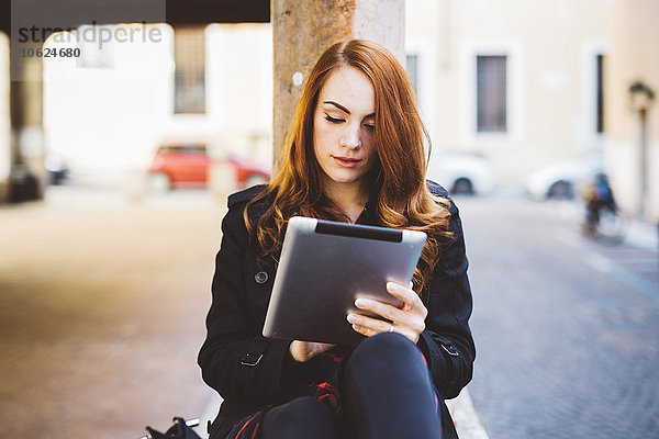 Junge Frau beim Betrachten des digitalen Tabletts im Freien