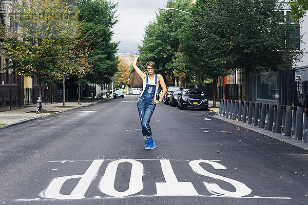 USA  New York City  Williamsburg  Frau in Jeans-Latzhose posierend auf der Straße