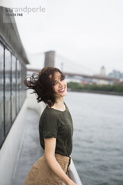 USA  New York City  Portrait einer jungen Frau  die an einem windigen Tag auf einem Ausflugsboot steht.