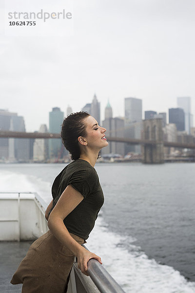 USA  New York City  junge Frau an einem windigen Tag auf einem Ausflugsboot stehend