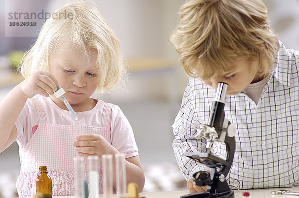 Zwei kleine Kinder spielen mit Utensilien des Chemielabors