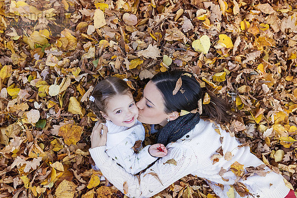 Mutter küsst Tochter im Herbstlaub