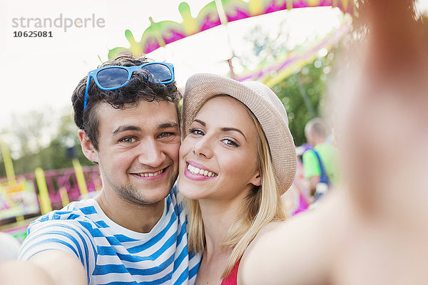 Glückliches Paar auf der Kirmes mit Selfie
