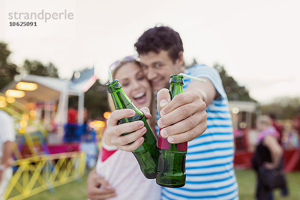 Fröhliches Paar auf der Kirmes beim Trinken von Erfrischungsgetränken