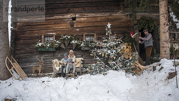 Österreich  Altenmarkt-Zauchensee  Familie vor dem Bauernhaus zur Weihnachtszeit
