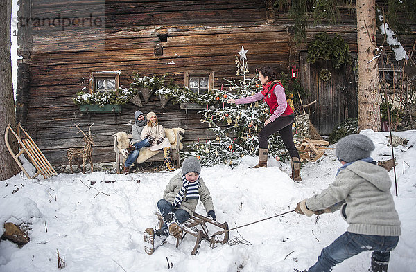 Österreich  Altenmarkt-Zauchensee  Familie vor dem Bauernhaus zur Weihnachtszeit