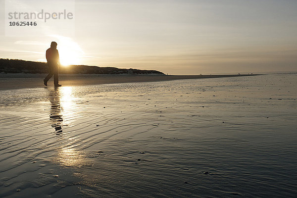 Deutschland  Insel Langeoog  Mann am Strand bei Sonnenuntergang