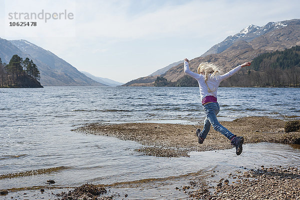 UK  Schottland  Schottische Highlands  Loch Shiel  Mädchen beim Springen über Wasser
