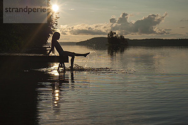 Finnland  Karelien  Uukuniemi  Pyhäjärvi-See  Mädchen auf dem Steg mit den Füßen im Wasser sitzend