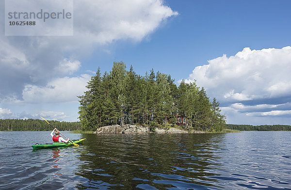 Finnland  Südsavonien  Oravi  Jungenkajak auf dem Saimaa-See zur kleinen Insel mit einsamer Hütte