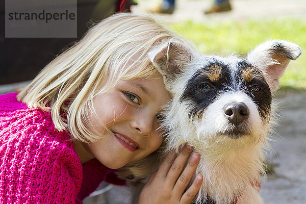 Porträt des lächelnden kleinen blonden Mädchens und ihres Jack Russel Terriers