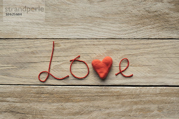 Das Wort Liebe besteht aus roten Fäden und einem Herz.