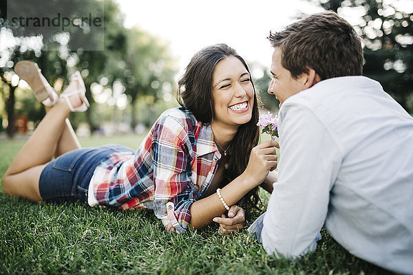 Verliebtes junges Paar auf einer Wiese im Park liegend