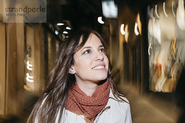 Spanien  Reus  Porträt einer lächelnden jungen Frau  die nachts durch die Stadt läuft.
