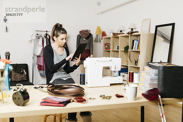 Junge Modedesignerin  die in ihrem Atelier mit digitalen Tabletts arbeitet.