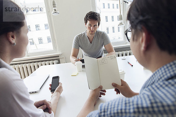 Drei kreative Geschäftsleute bei einem Meeting in einem modernen Büro