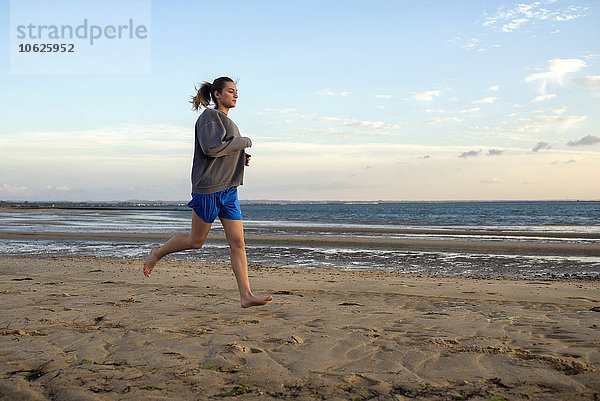Spanien  Puerto Real  junge Frau beim Joggen am Strand in der Abenddämmerung