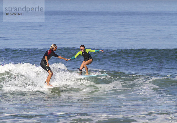 Mann hilft Frau auf dem Surfbrett