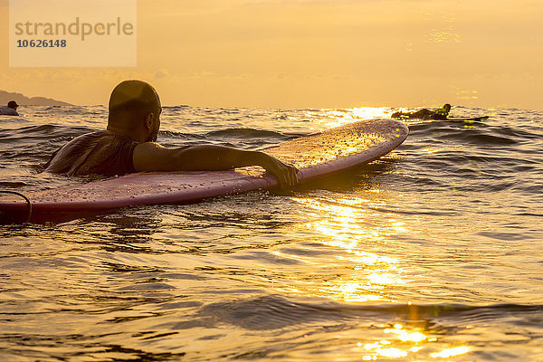 Surfer mit Surfbrett im Abendlicht