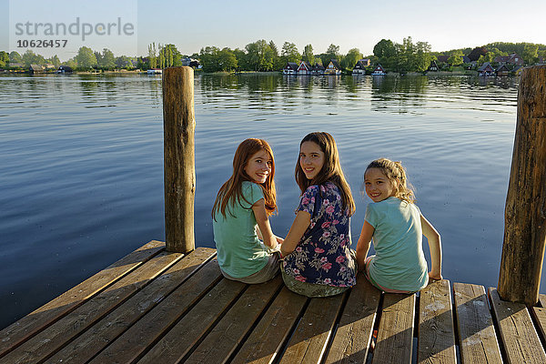 Deutschland  Mirow  drei Mädchen sitzen auf einem Steg am Lake Mirow