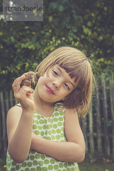 Porträt eines lächelnden kleinen Mädchens mit Weinbergschnecke