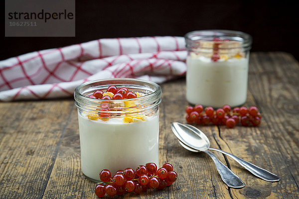 Glas Joghurt mit Müsli  Cornflakes und roten Johannisbeeren