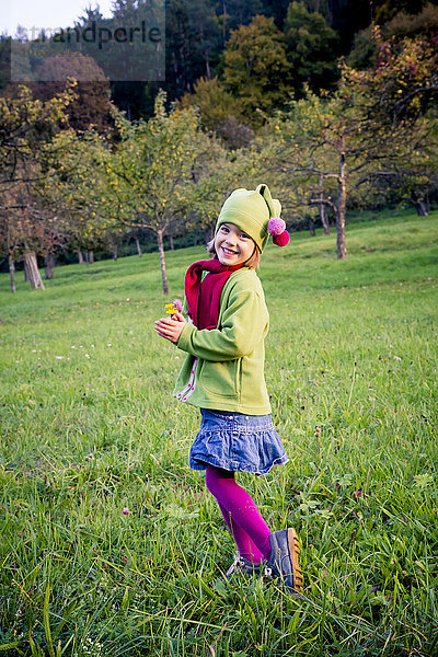 Deutschland  Baden-Württemberg  lächelndes kleines Mädchen auf einer Wiese im Herbst