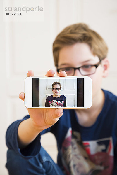 Junge zeigt mit seinem Porträt auf dem Display