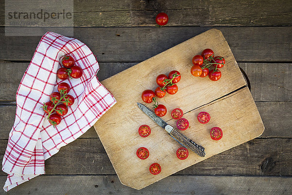 Küchentuch und geschnittene und ganze Tomaten auf dem Schneidebrett