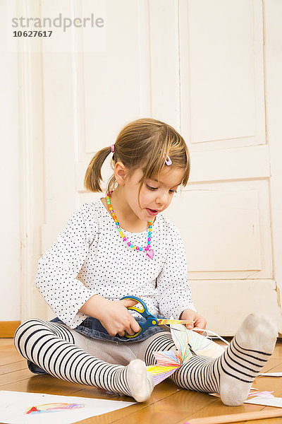 Kleines Mädchen beim Basteln mit Papier und Schere