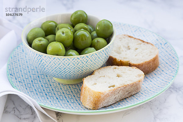 Schale mit grünen Oliven und Brotscheiben auf dem Teller