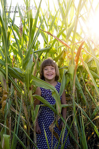 Glückliches kleines Mädchen  das in einem Kornfeld steht.