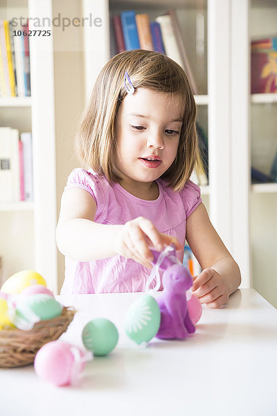 Kleines Mädchen spielt mit Ostereiern und Osterhase