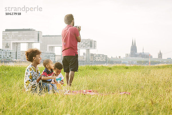Deutschland  Köln  vierköpfige Familie mit Decke auf einem Feld