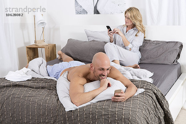 Reife Paare im Schlafzimmer mit ihren Handys