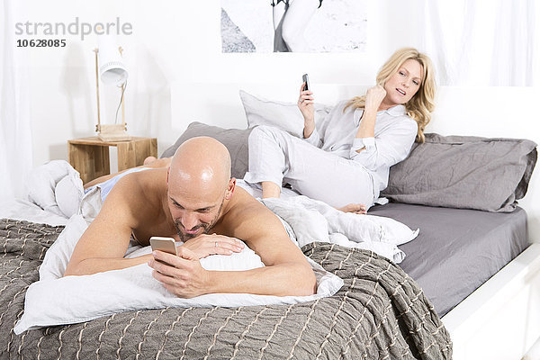 Reife Paare im Schlafzimmer mit ihren Handys