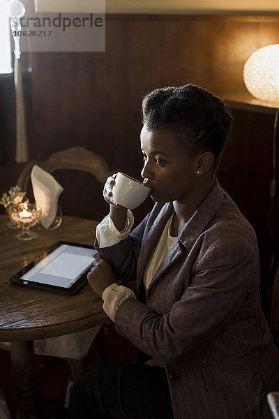 Junge Frau sitzt in einem Café und trinkt Kaffee.